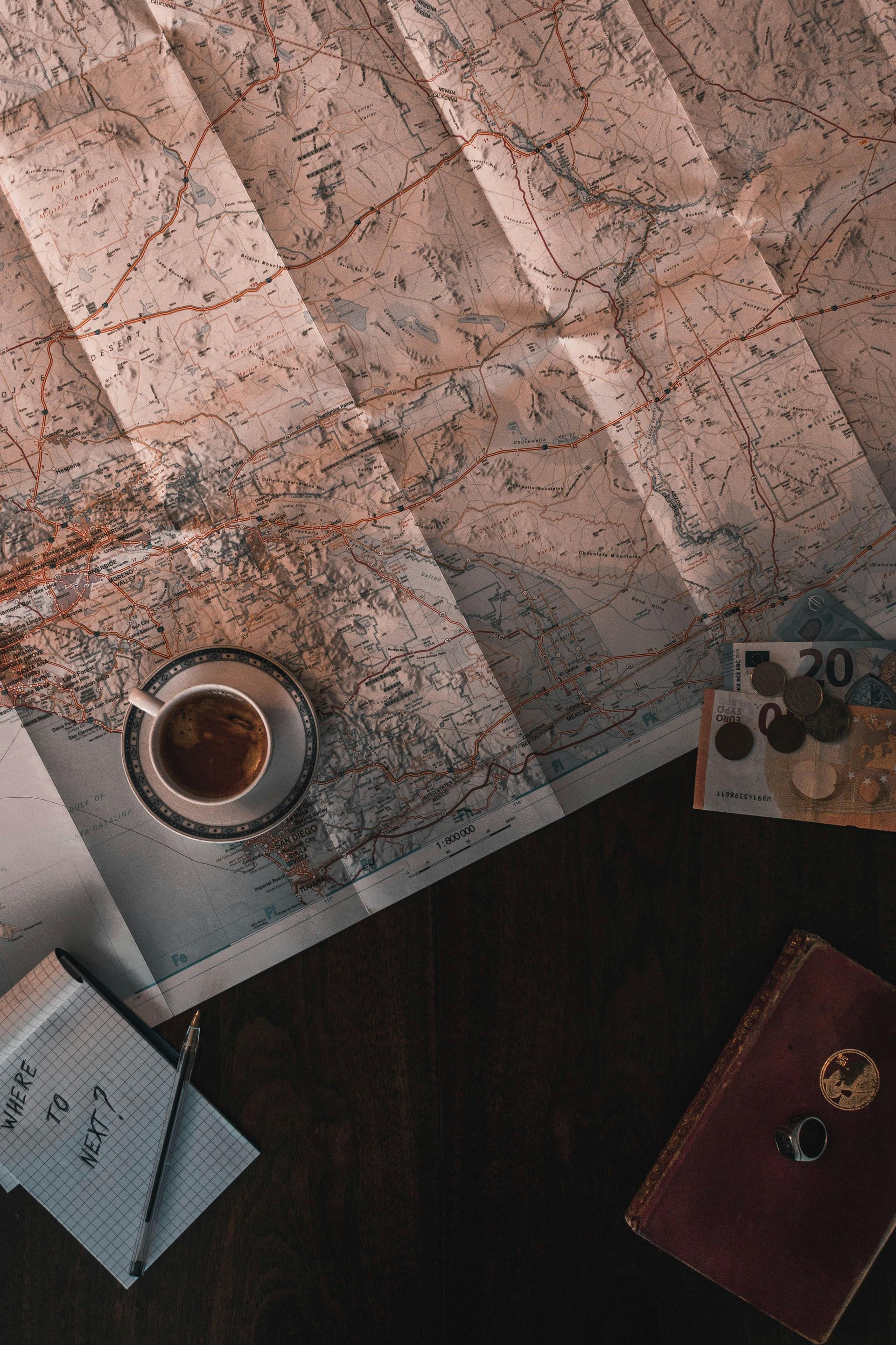 A cup of coffee is sitting on top of a map on a table - Carmen & Co Consulting Strategic Consulting in Southeast Queensland