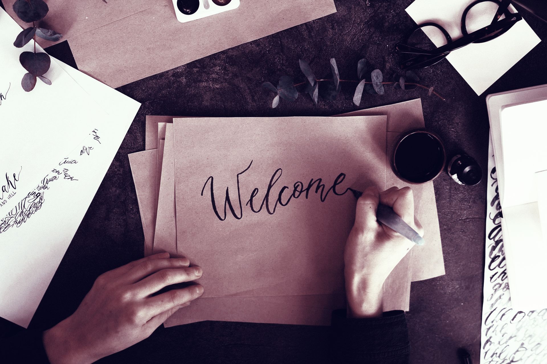 A person is writing the word welcome on a piece of paper.