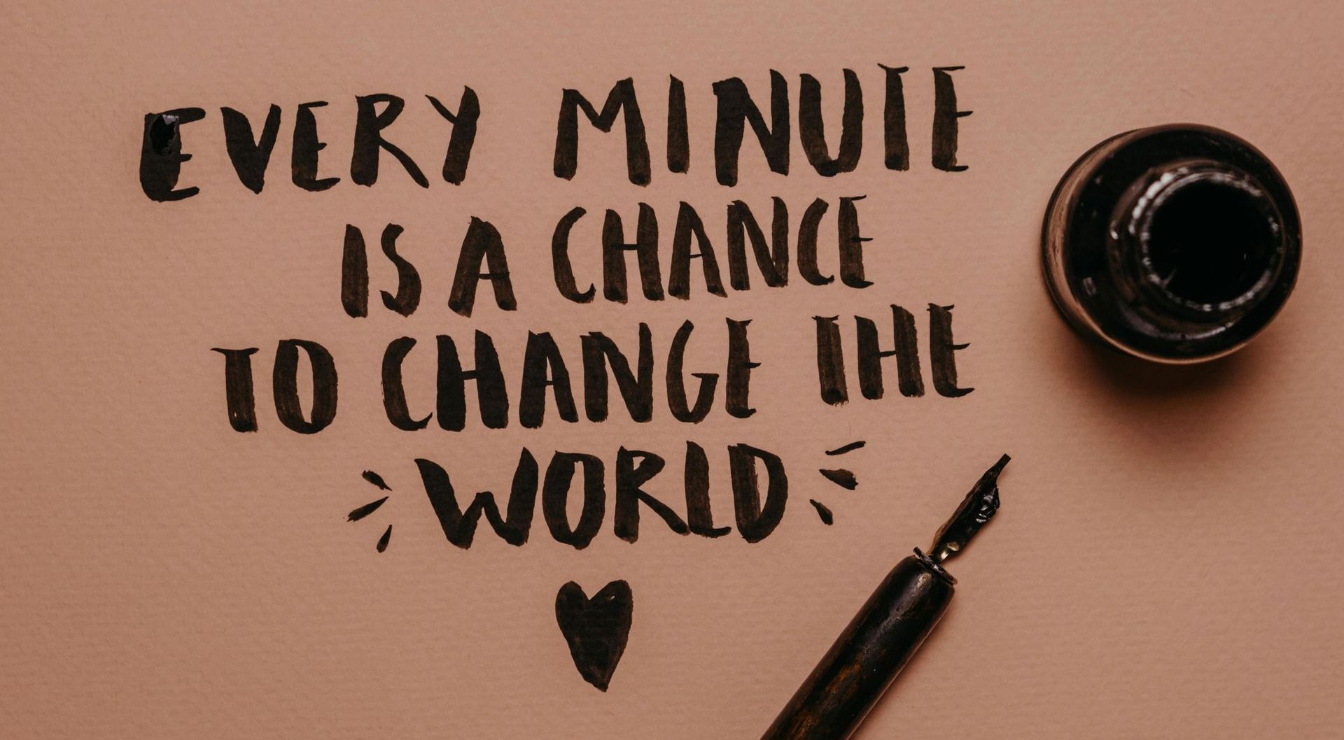 A rose gold coloured sheet with a fountain pen laying on it that has just written 'every minute is a chance to change the world - Carmen & Co Consulting Strategic Consulting in Southeast Queensland