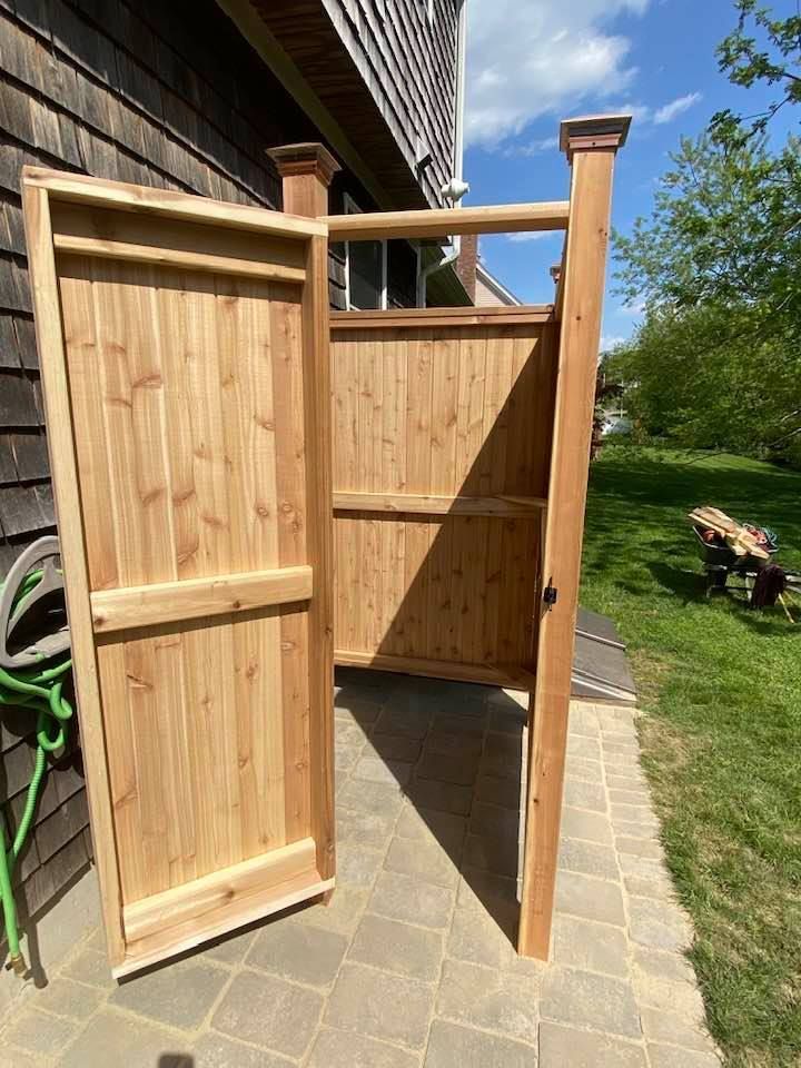 Open wooden garden gate beside a brick house on a sunlit patio