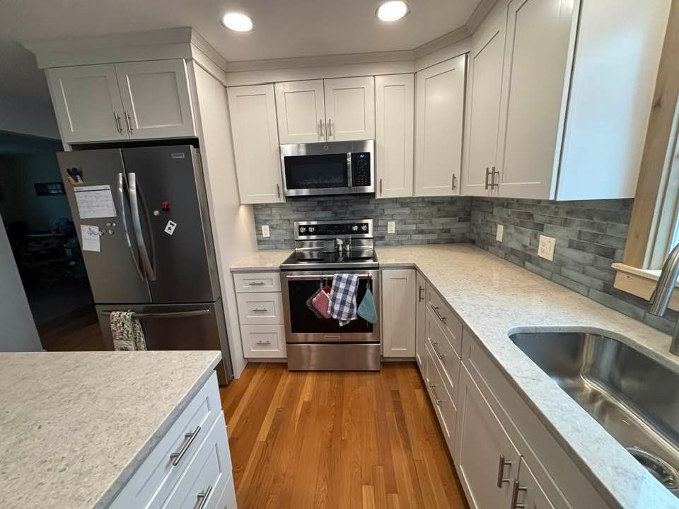 Bright modern kitchen with white cabinets, stainless steel appliances, and wood floor