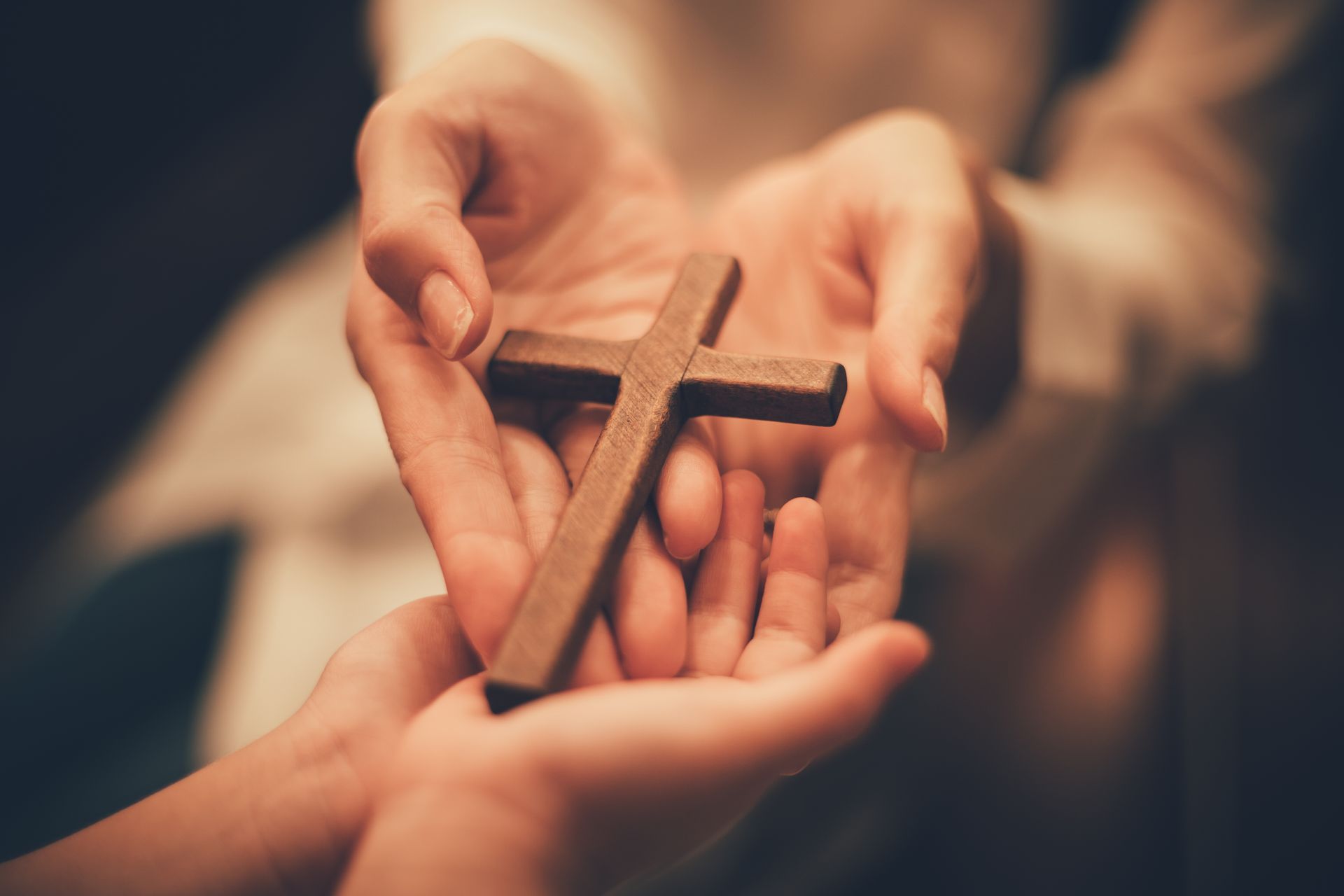 A person is holding a wooden cross in their hands.