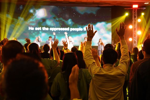 A crowd of people are raising their hands in the air at a concert.