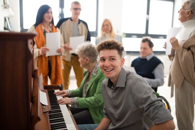 A young man is playing a piano in front of a group of people.