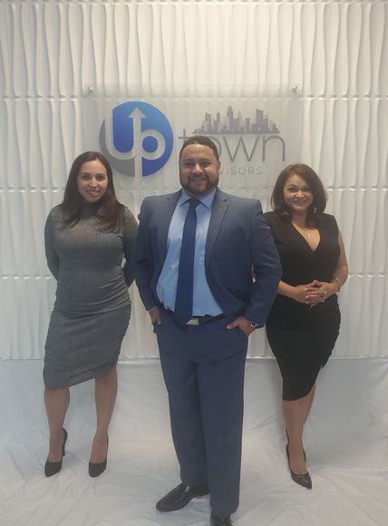 Three professionals stand in front of a white