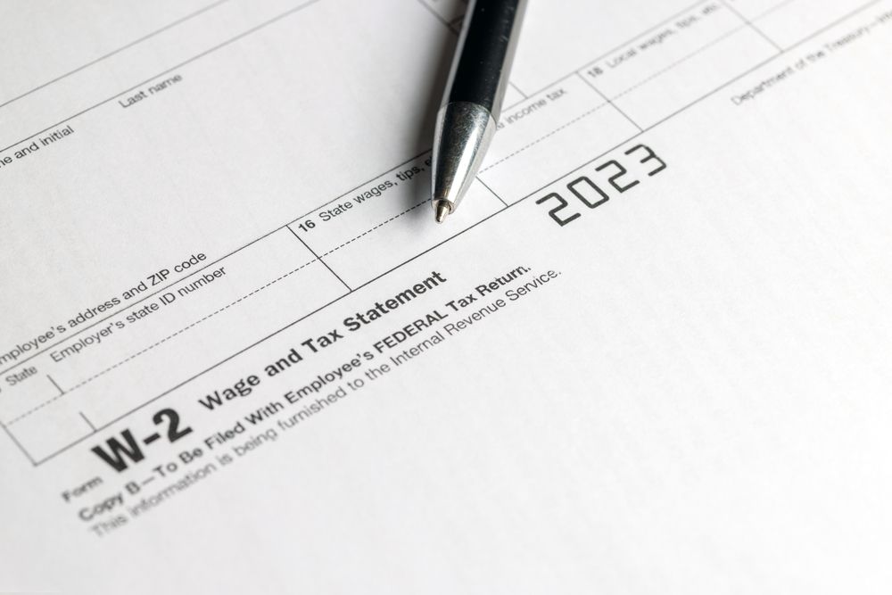 A close-up view of a 2023 IRS Form W-2, Wage and Tax Statement, with a pen resting on top of the document.