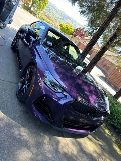 A purple bmw m4 is parked on the side of the road.