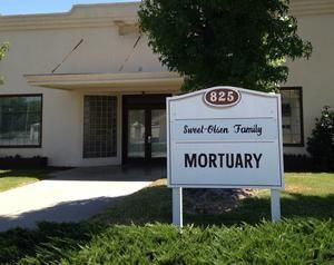 Small beige building with a sign reading “MORTUARY” and “Sweet-Olsen Family” at the entrance