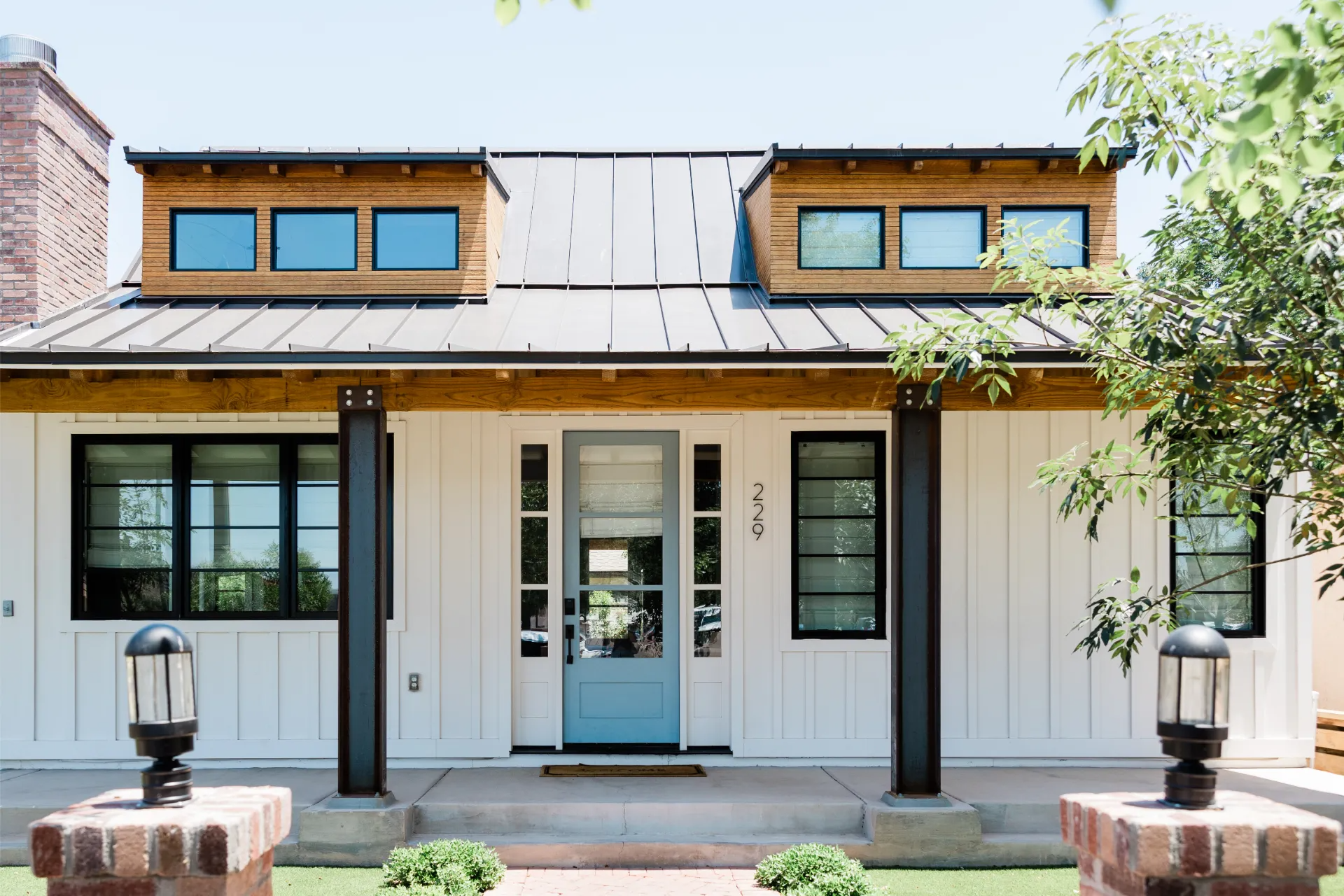 Modern white house with blue door, black windows, and wood accents.