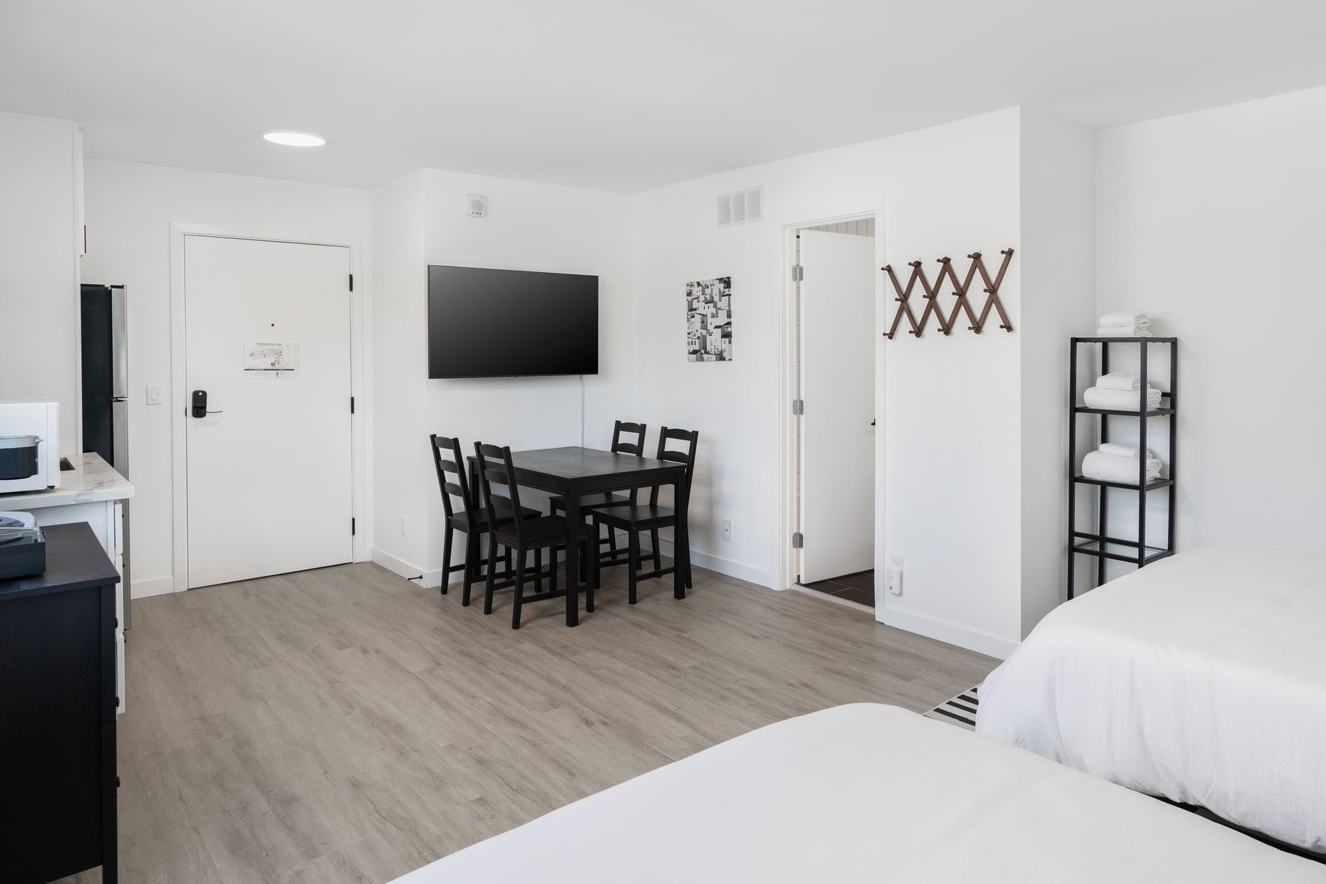 A hotel room with a dining table, TV, and beds