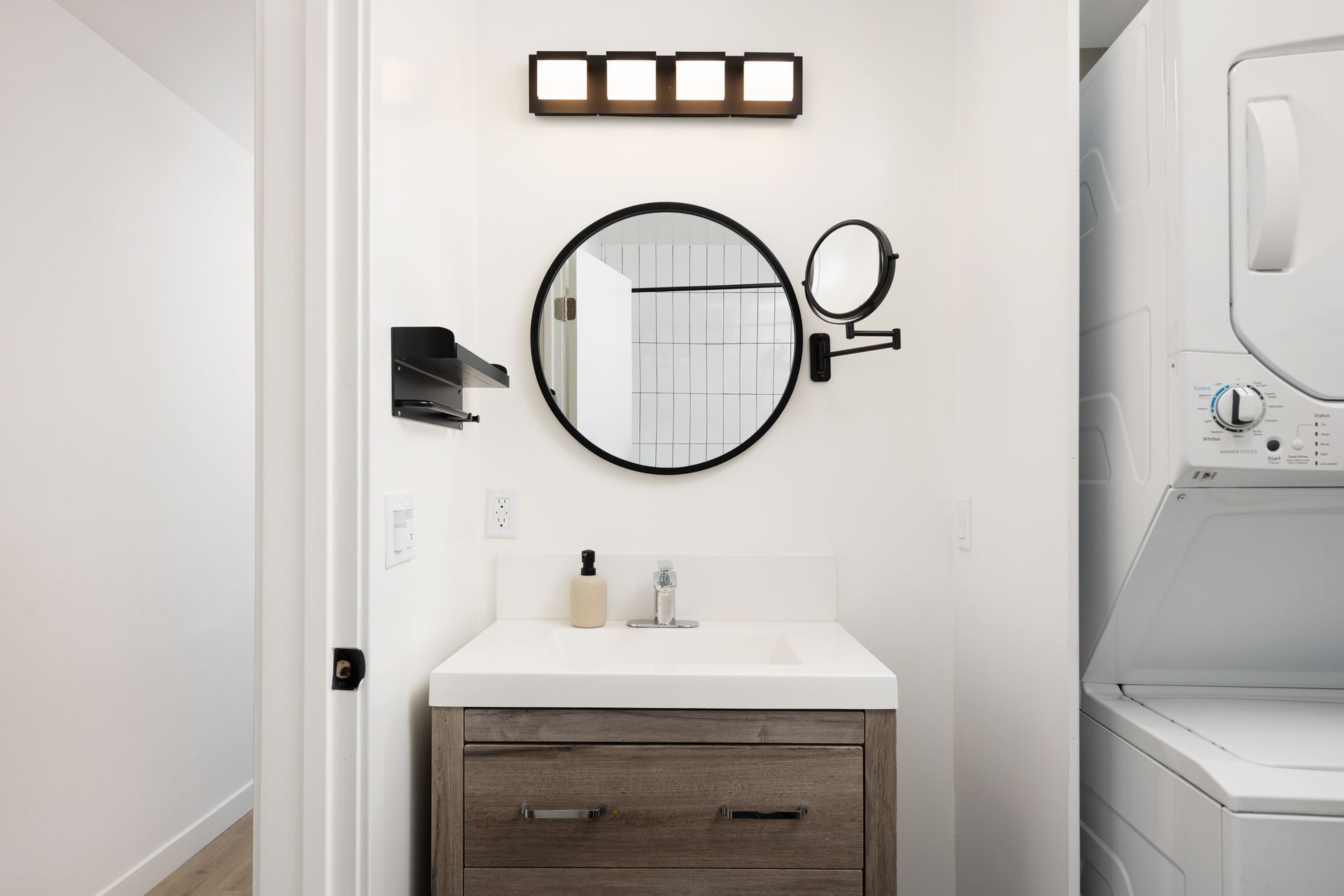 A clean bathroom with a sink, mirror, and stacked washer dryer