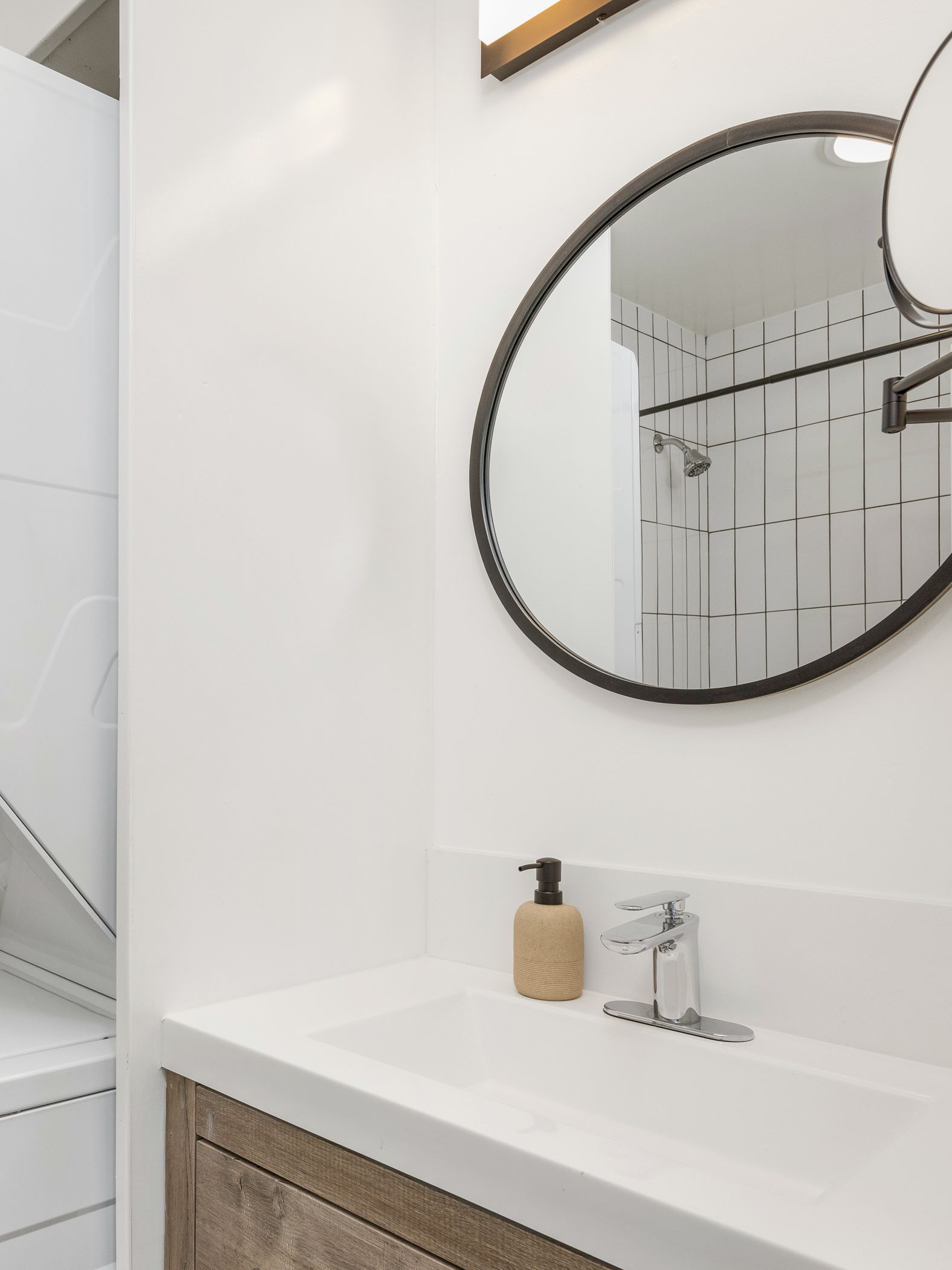 A bathroom sink with a mirror above it and a shower in the reflection.