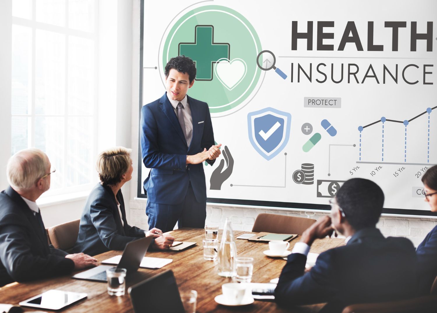 Man presenting health insurance options to a group in a conference room.