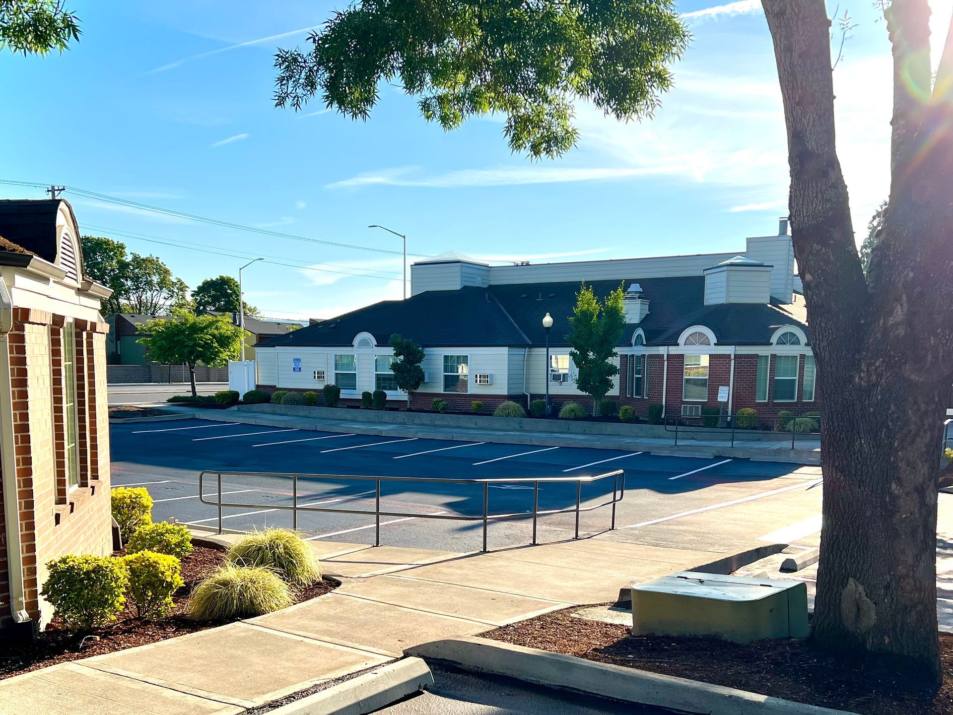 Daytime exterior of a building with a parking lot and a tree in the foreground.