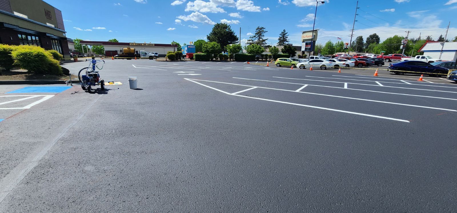 A parking lot with several vehicles, including an electric scooter, under a bright blue sky.