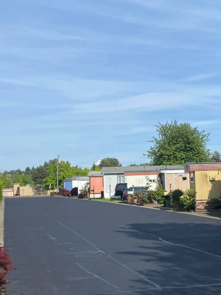 Mobile homes line a paved road under a blue sky, some with colorful facades.