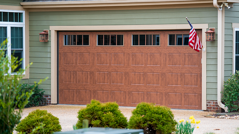 Wooden garage door on a house exterior with small windows and an American flag