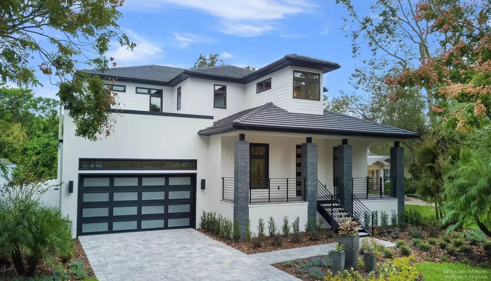 White garage door opening at a stone-sided driveway entrance, with a hand visible on the right.