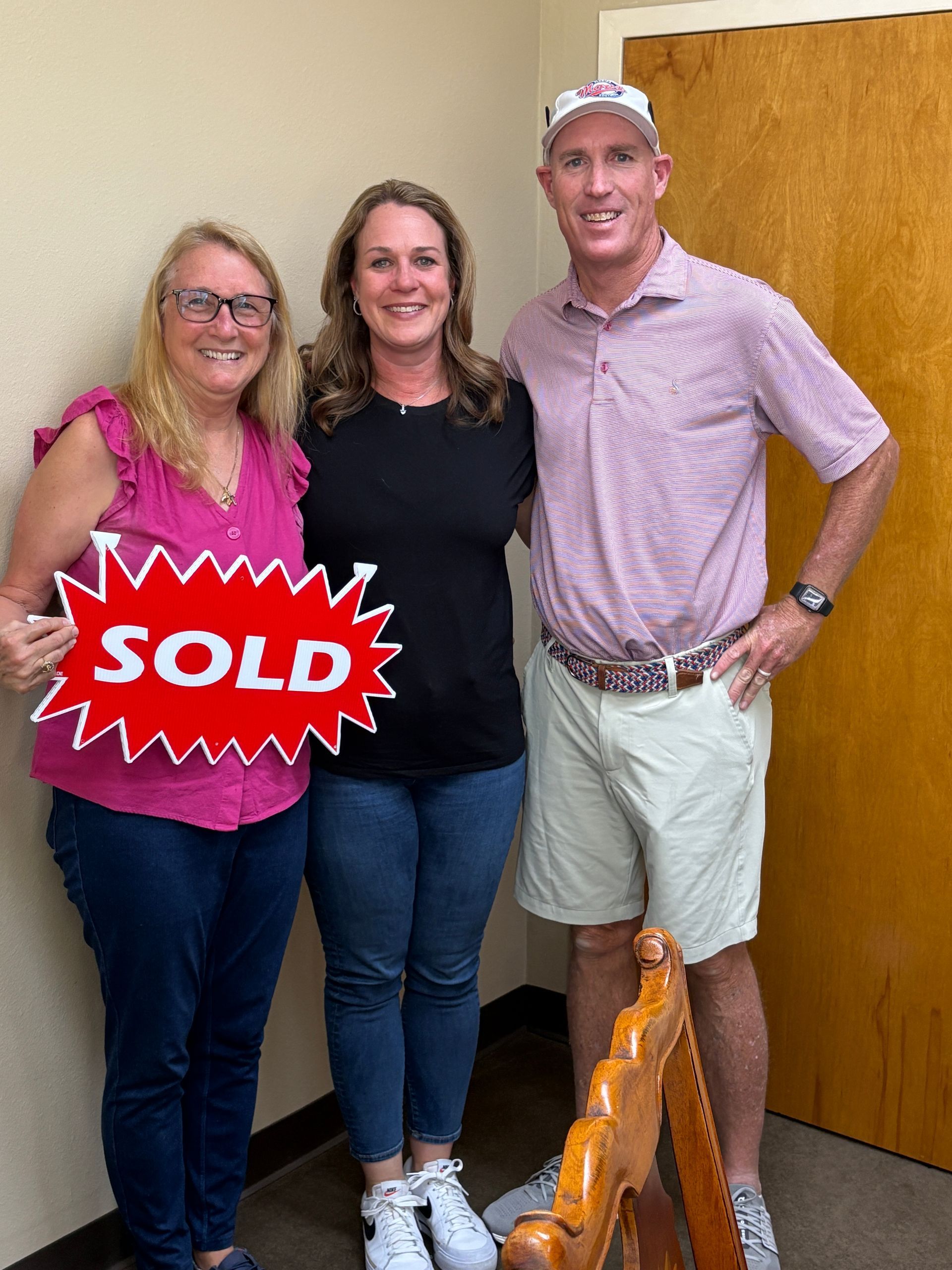 Three people standing indoors with a red 