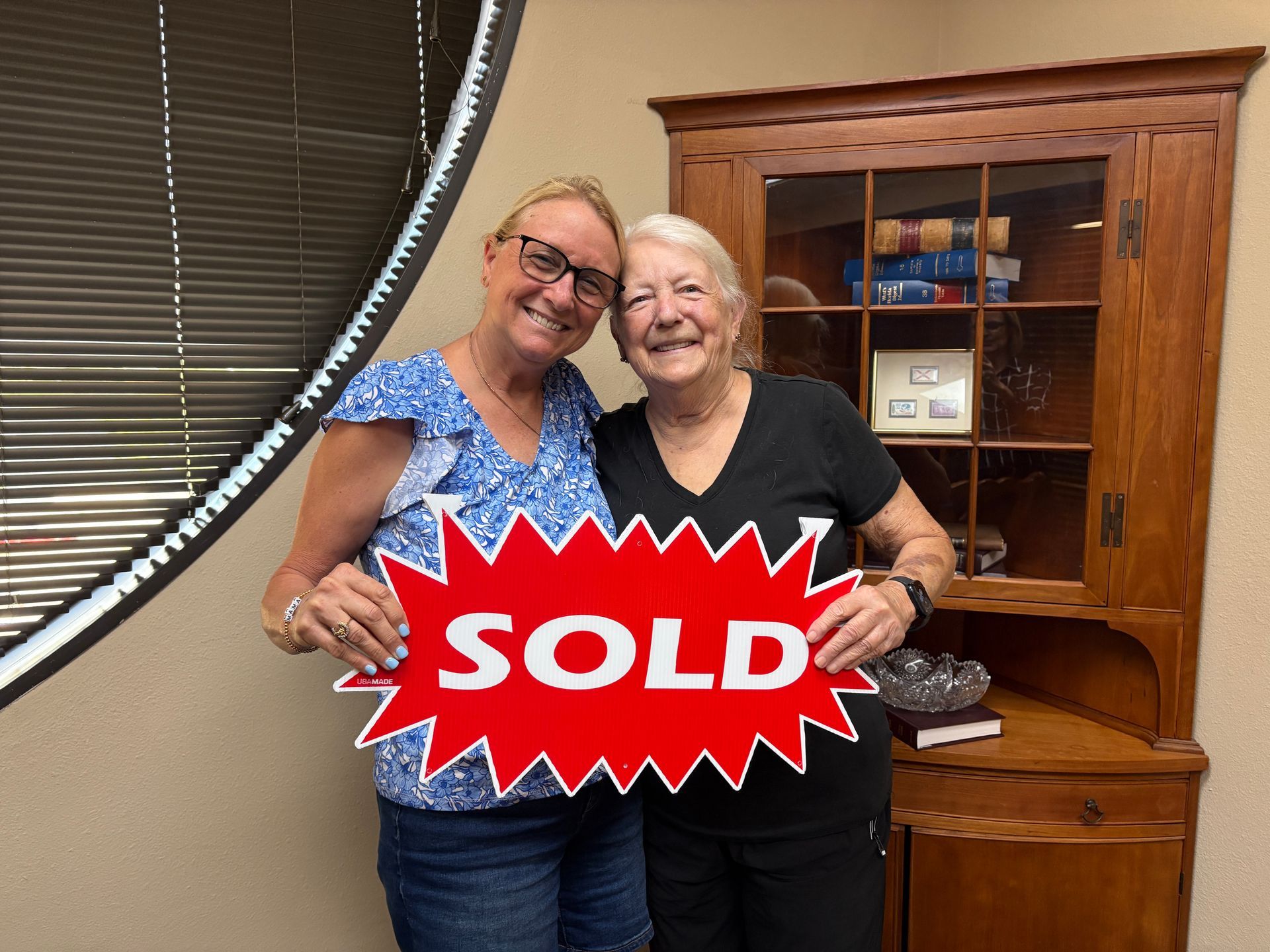 Two smiling women hold a red 