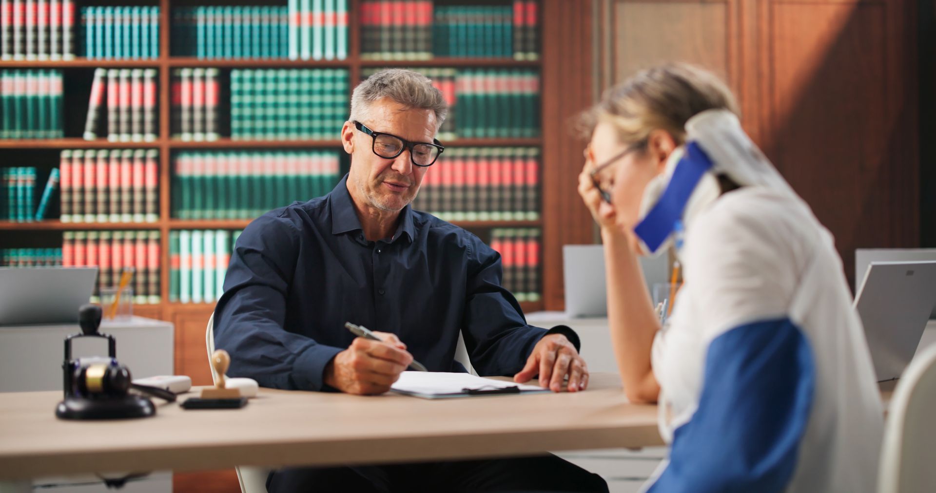 Lawyer meeting with a client at a desk in a library, reviewing documents.