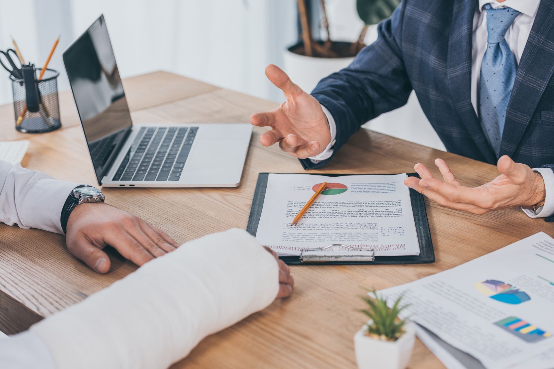 Business meeting around a laptop and clipboard with charts on a desk