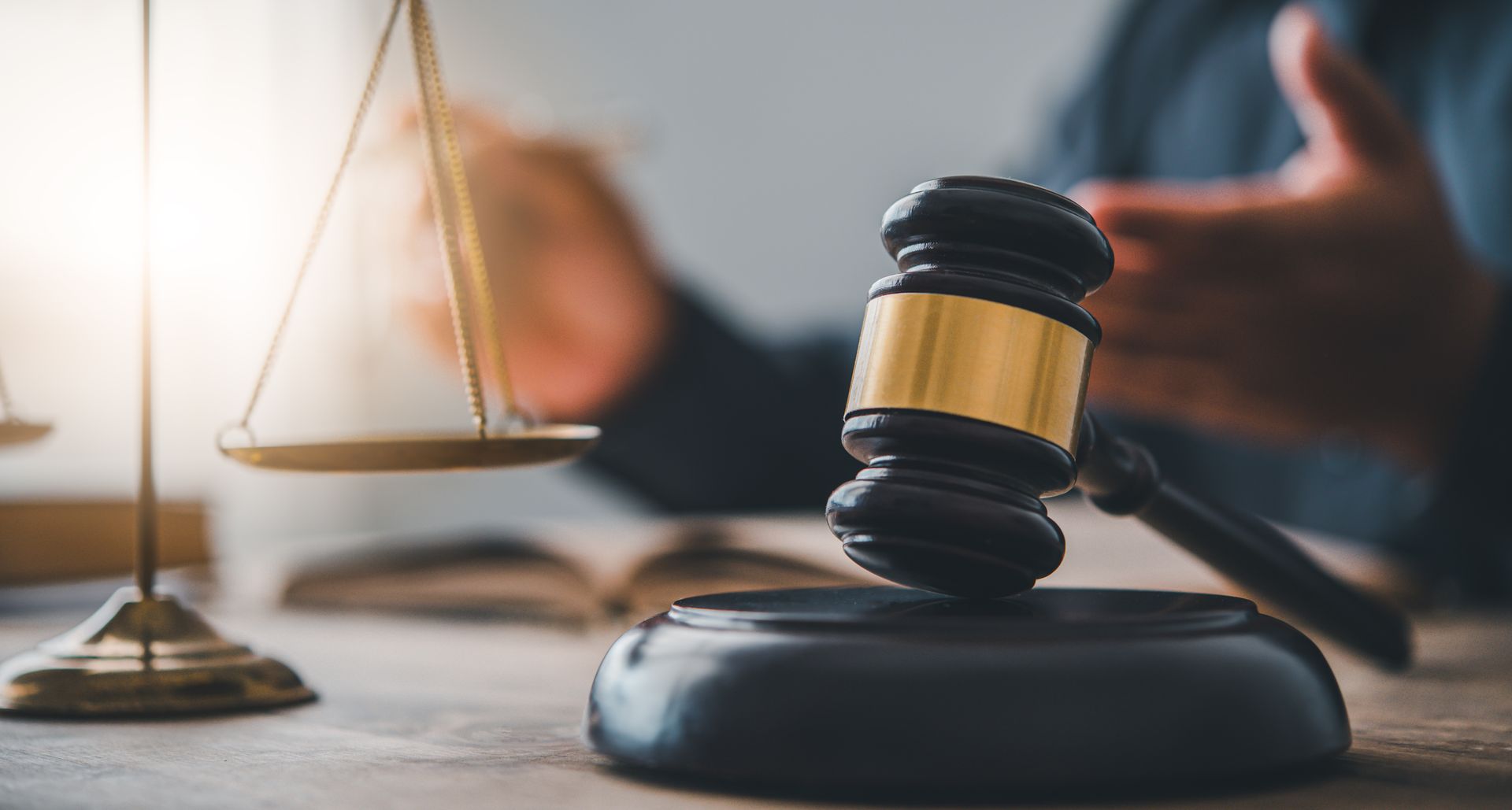 Lawyer’s desk with gavel, scales of justice, and blurred person in background