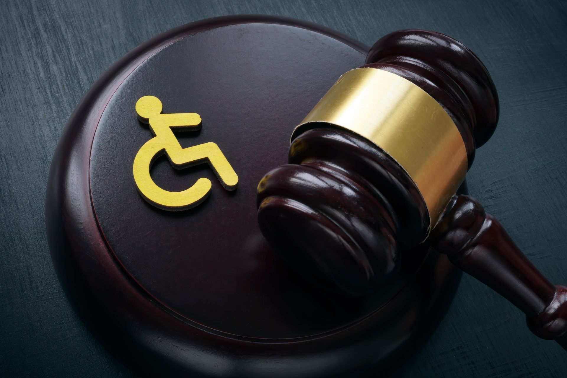 Yellow disability symbol on a gavel and black judge’s block, symbolizing accessibility and law