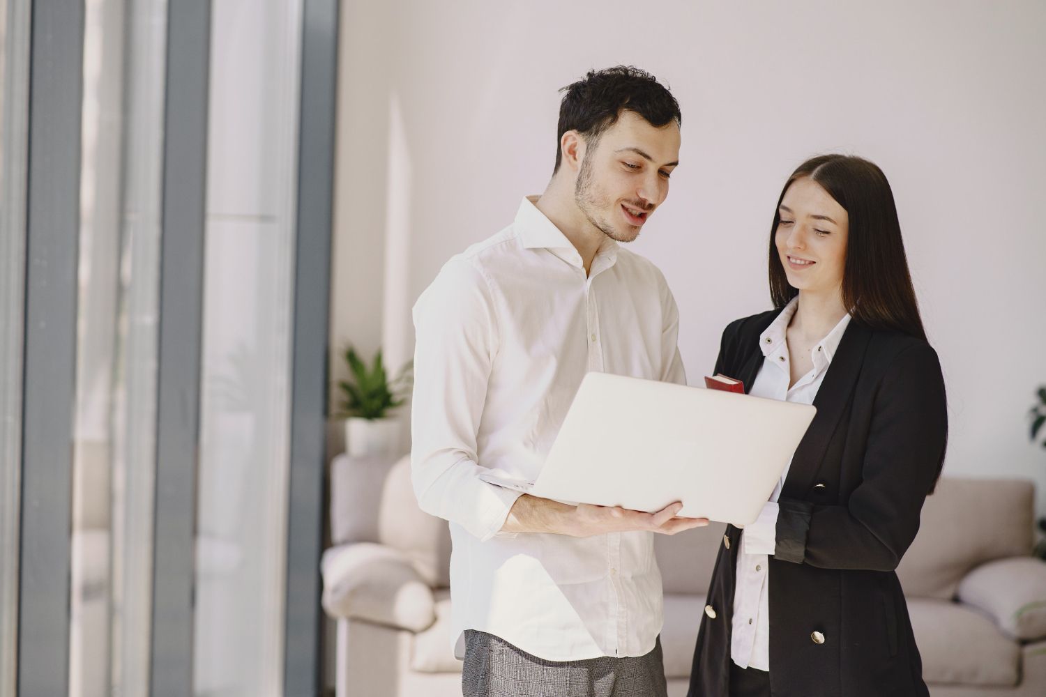 Two people review paperwork and sign a document beside a small building model on a desk