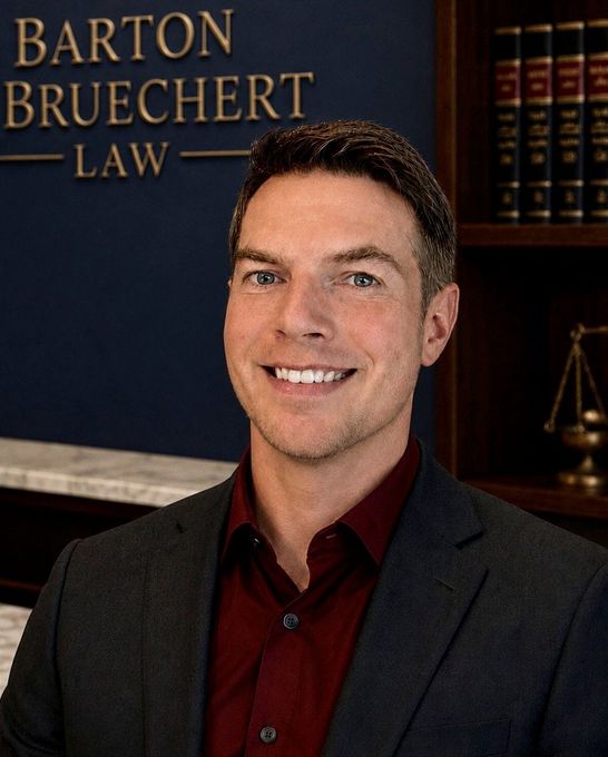 Portrait of a smiling attorney in a dark suit before a law office backdrop with books and scales of justice