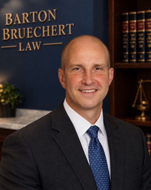 Smiling attorney in a suit before a Barton Bruechert Law office backdrop