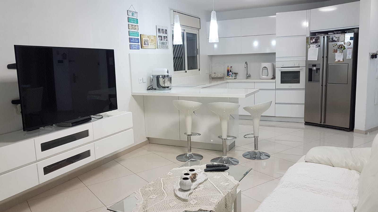 סלון עם טלוויזיה בעלת מסך שטוח, ספה, שולחן ומקרר.
