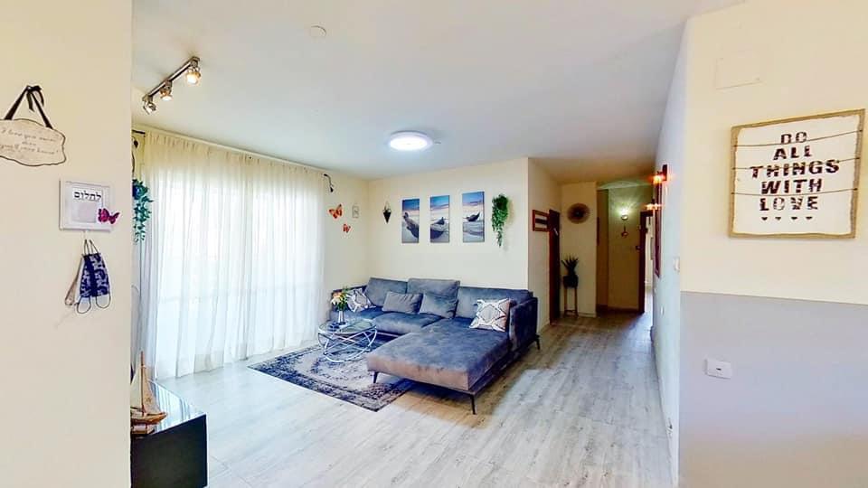 סלון עם ספה ושלט על הקיר שאומר ''כל הדברים באהבה''.