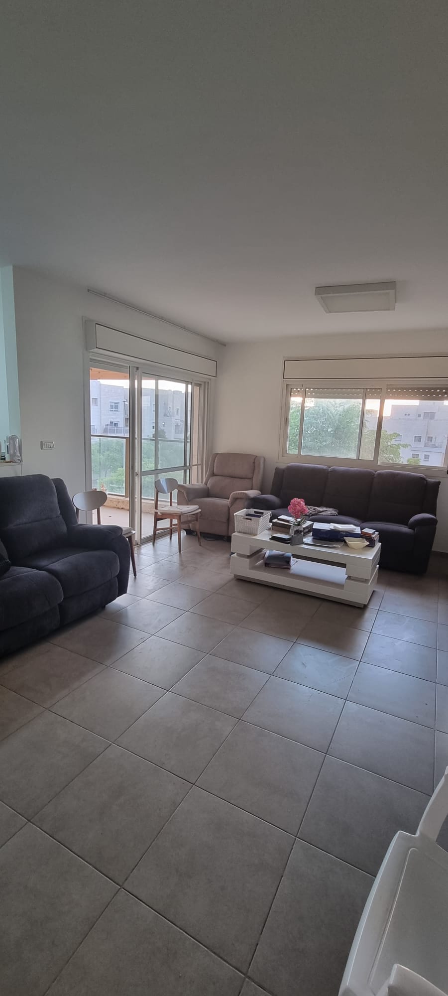 סלון עם ספה, כיסא, שולחן קפה ודלתות הזזה מזכוכית.
