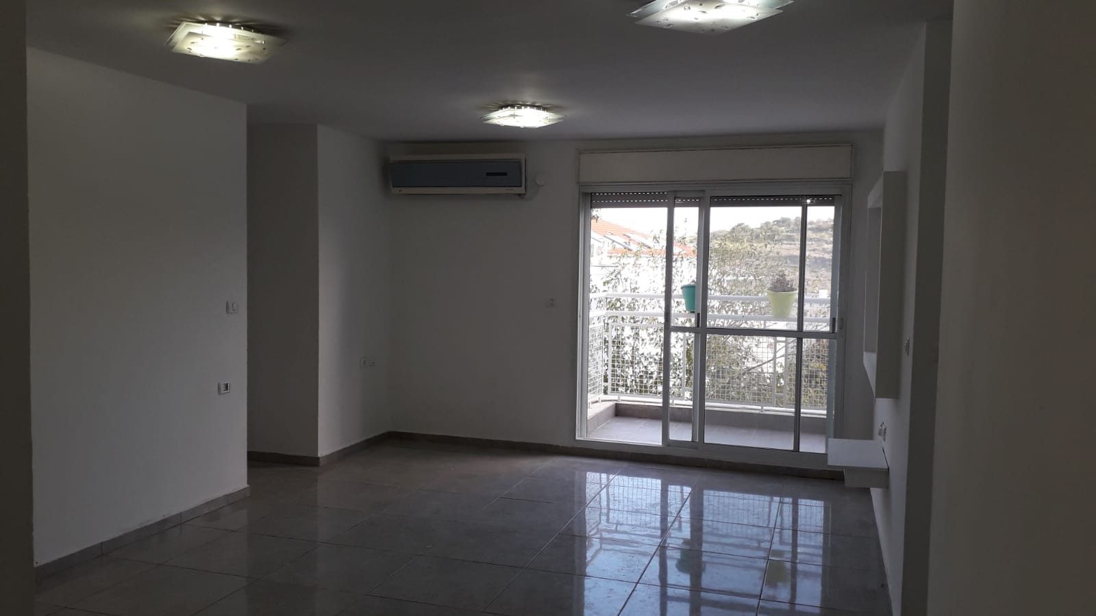 סלון ריק עם מרפסת ודלתות הזזה מזכוכית