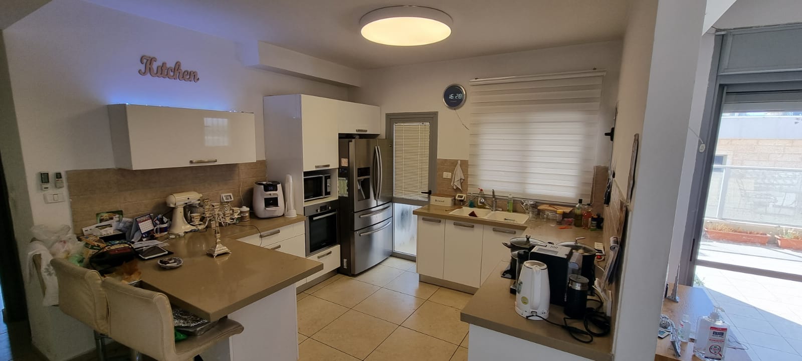 מטבח עם ארונות לבנים ומכשירי נירוסטה.