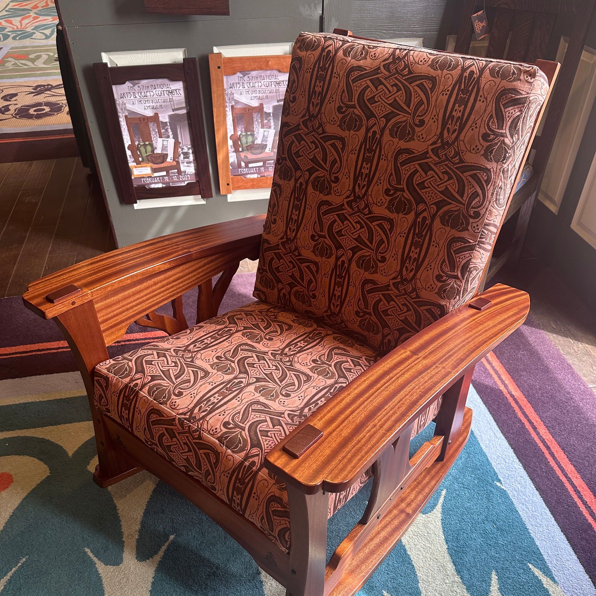 A wooden rocking chair with a patterned cushion is sitting on a rug.