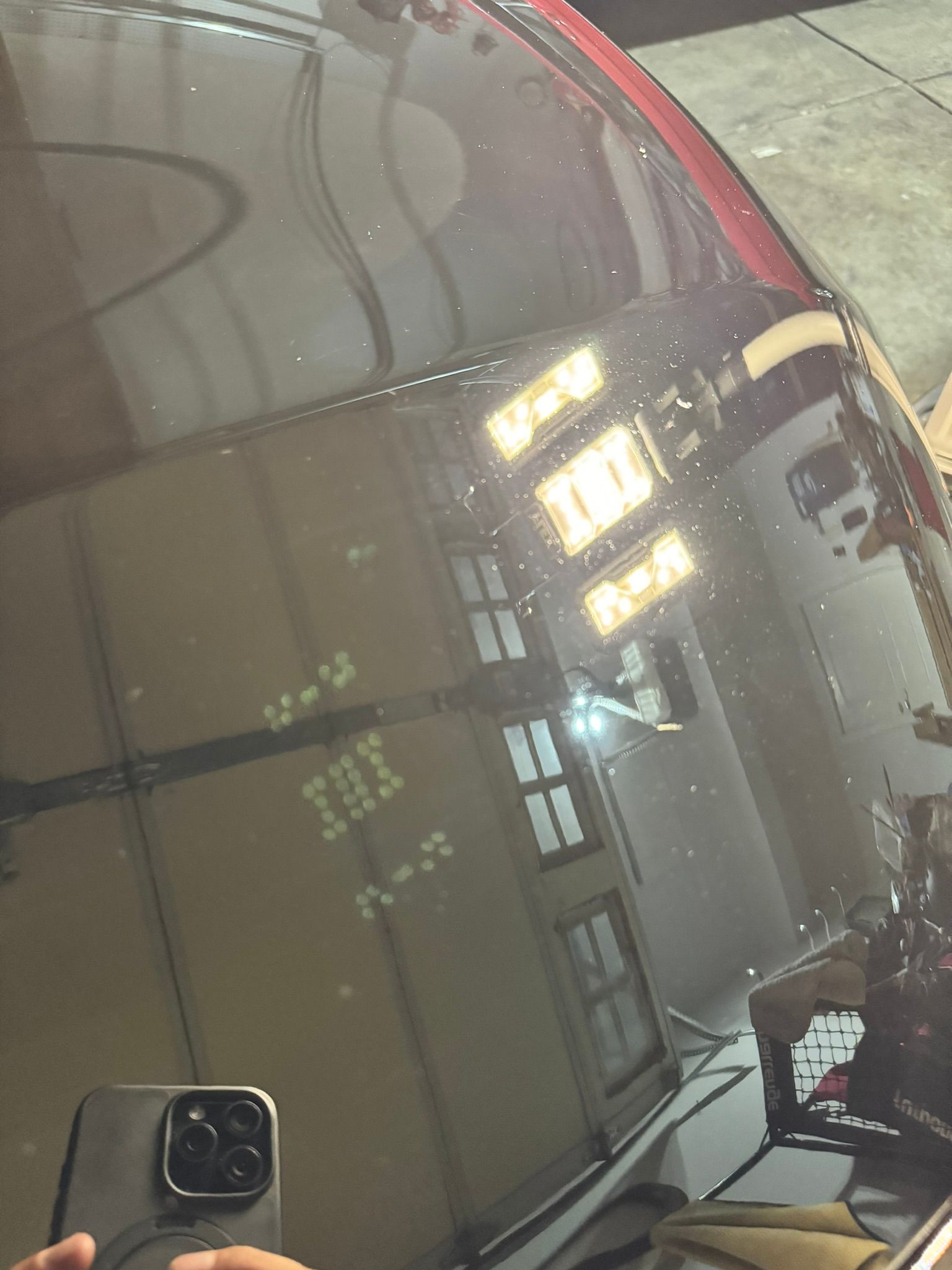 A person is taking a picture of a car with a cell phone
