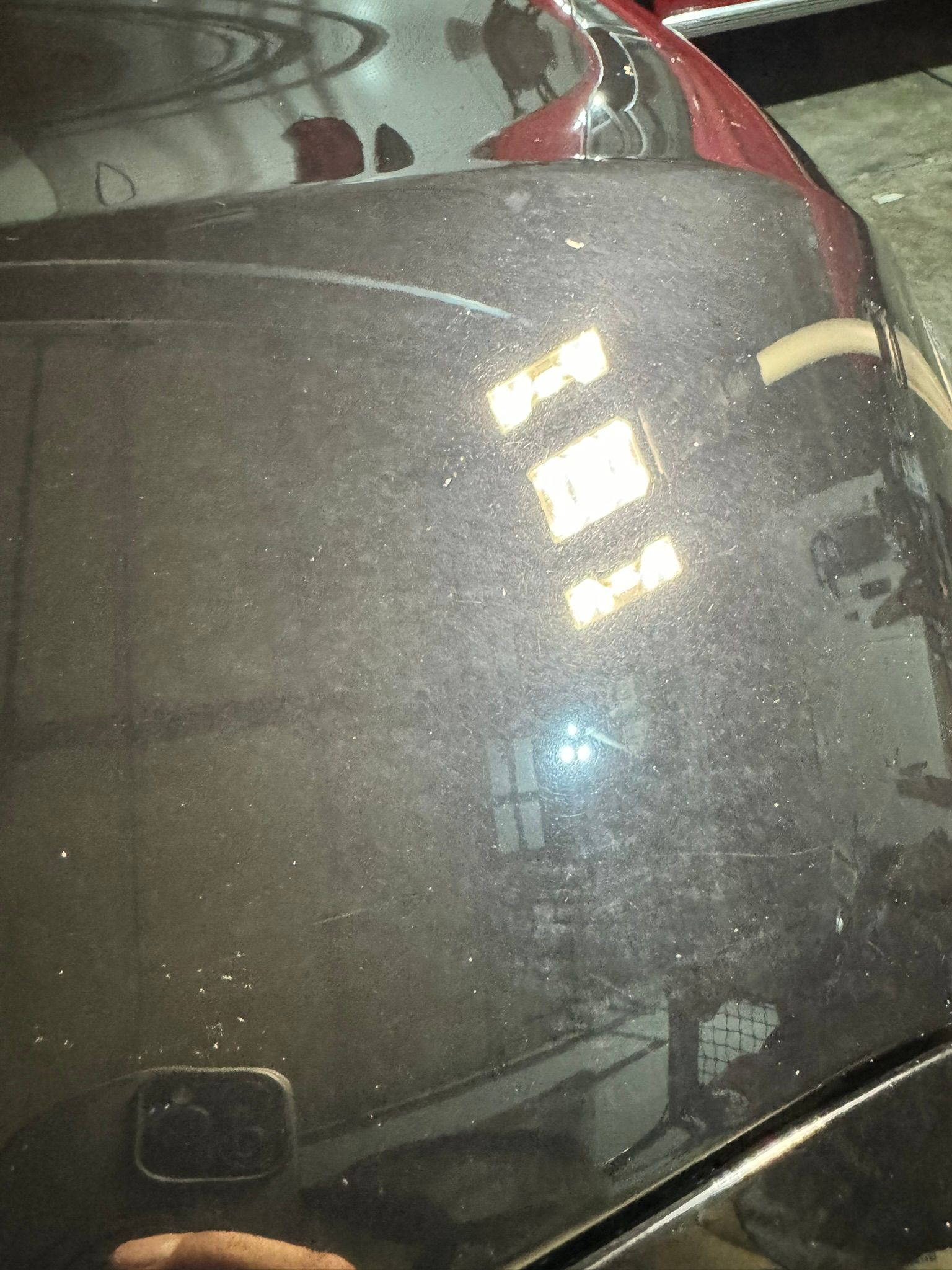 A person is taking a picture of the hood of a car