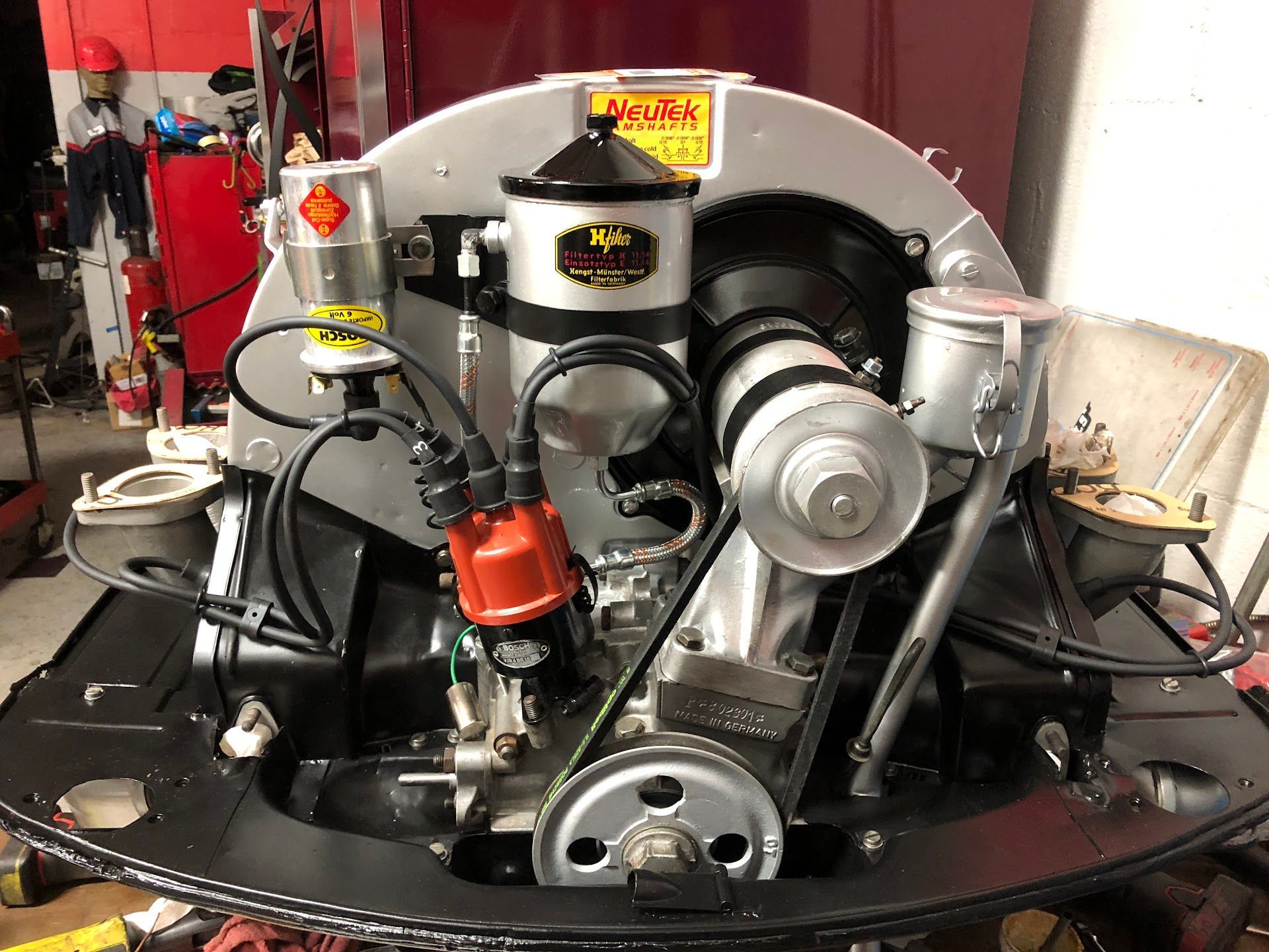 Black Volkswagen engine with silver components, red distributor, and yellow accents, set in a workshop. | Rose Brothers Garage