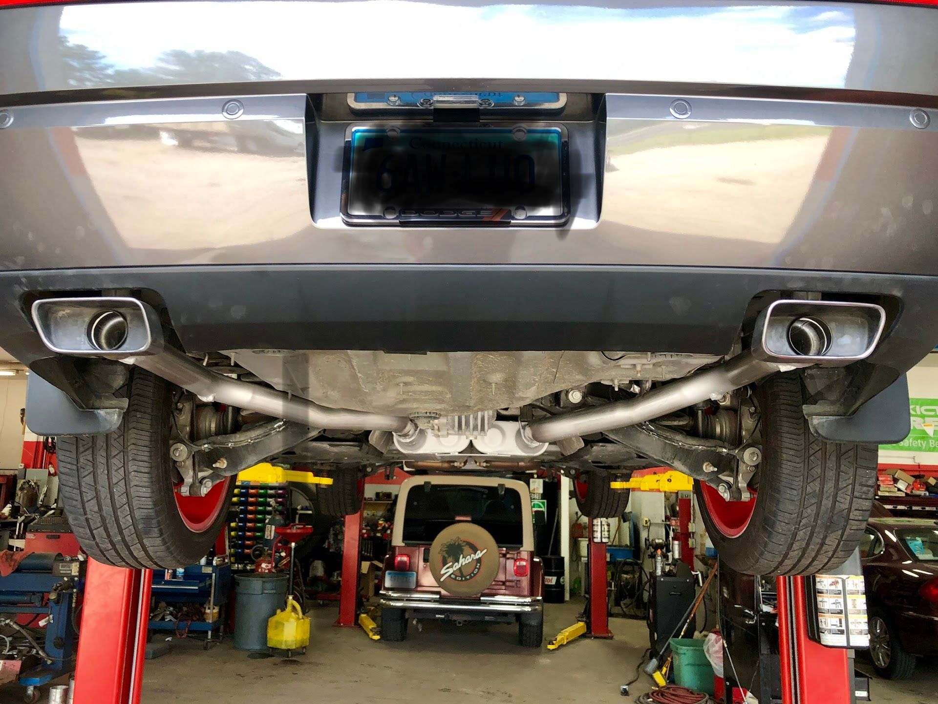 Car on a lift, exhaust system visible. Dual chrome exhaust tips, undercarriage, shop setting. | Rose Brothers Garage