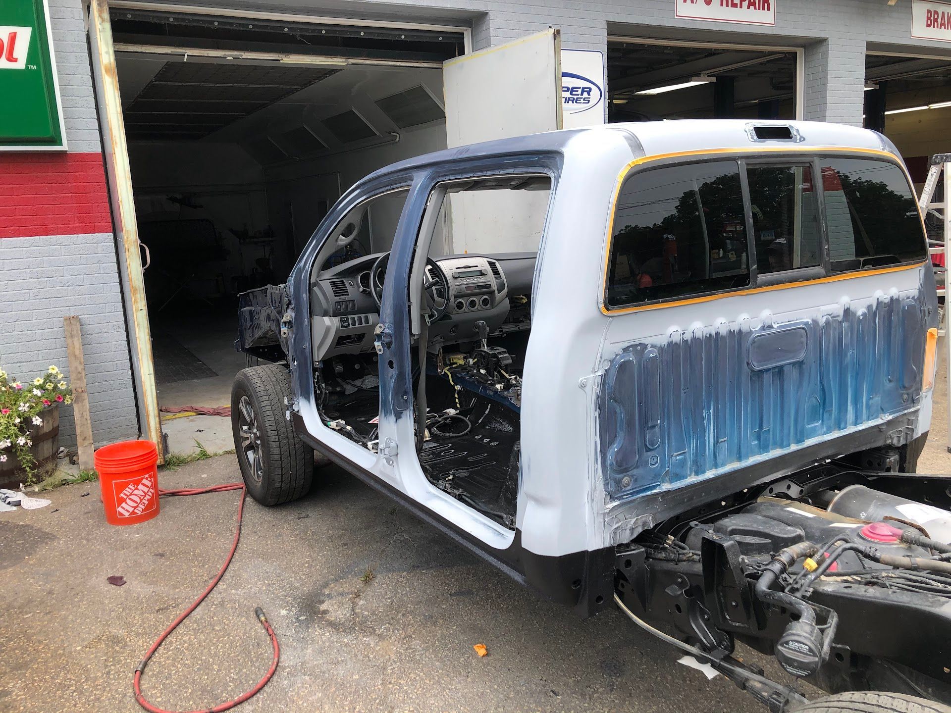 Truck cab in a body shop, partially painted, interior exposed, with tools and a spray gun nearby. | Rose Brothers Garage