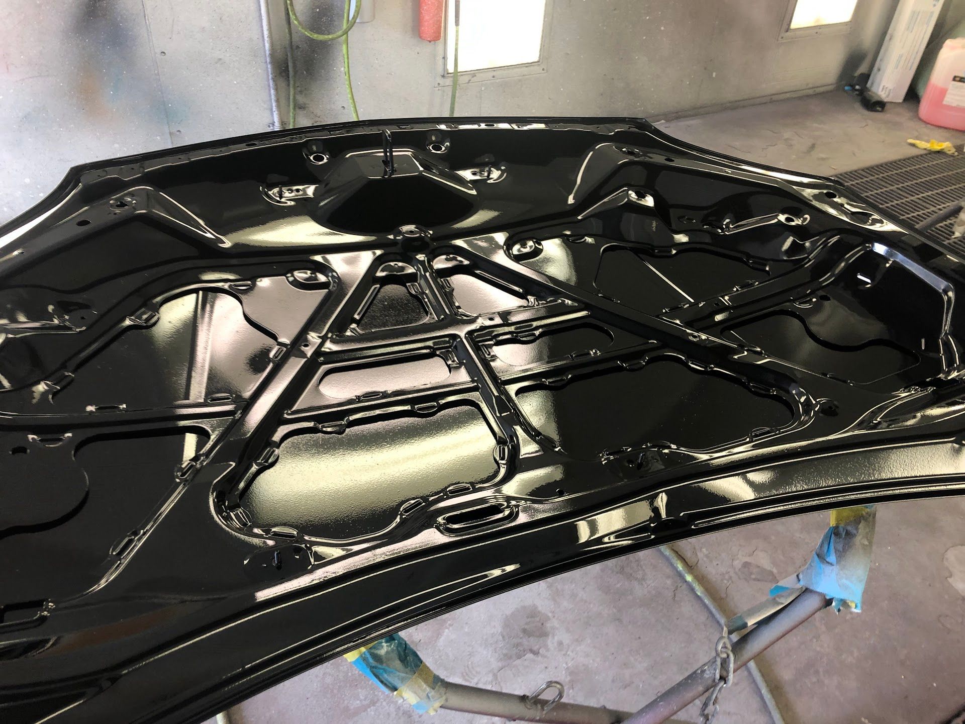 Black painted car hood interior, shiny finish in a workshop. | Rose Brothers Garage