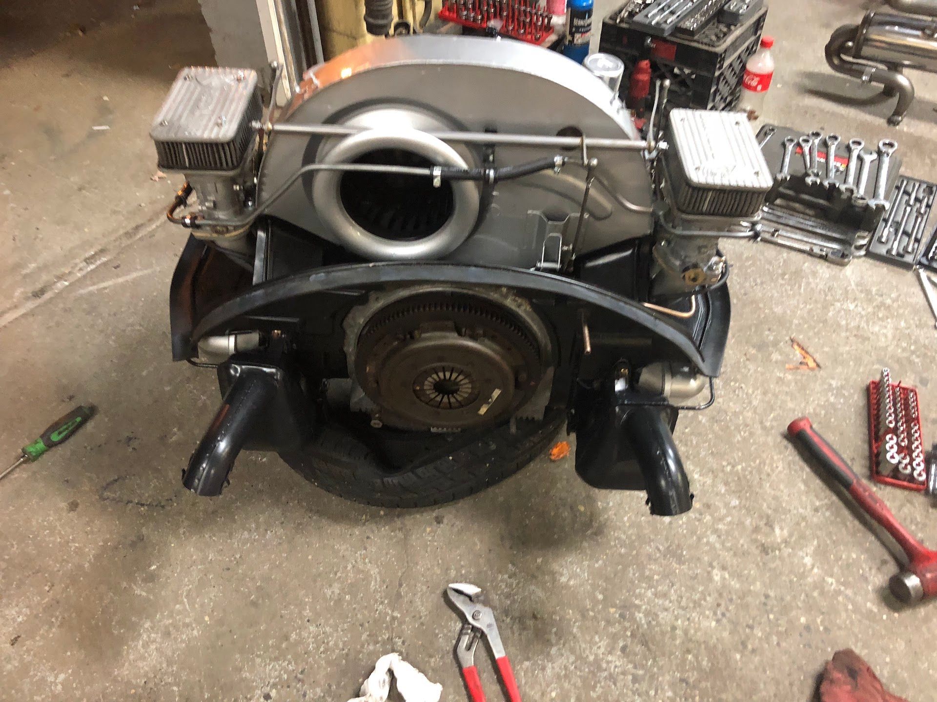 Volkswagen engine with dual carburetors, black exhaust, and gray air filter in a workshop. | Rose Brothers Garage