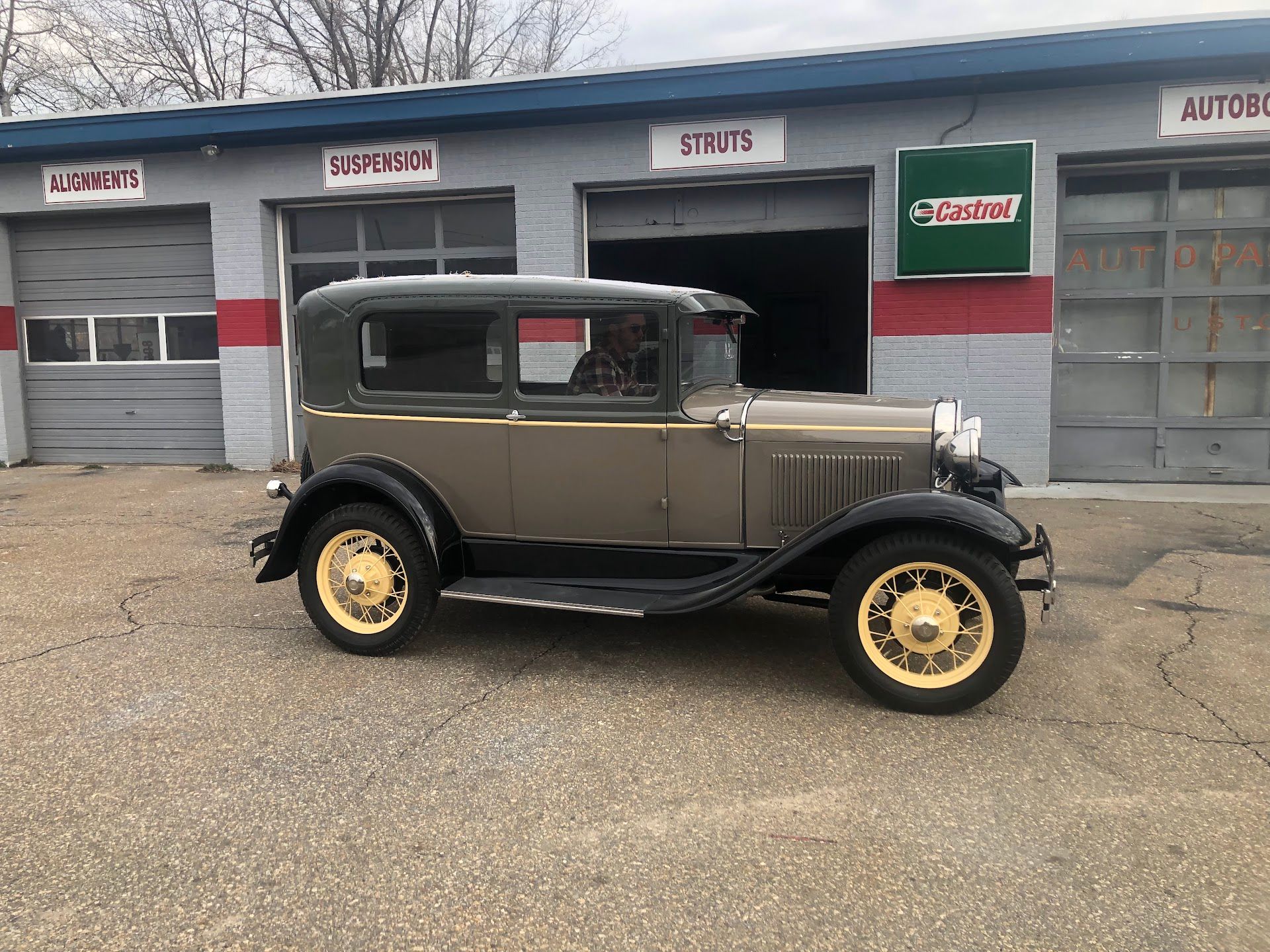 Vintage brown car parked in front of an auto repair shop with open garage doors. | Rose Brothers Garage
