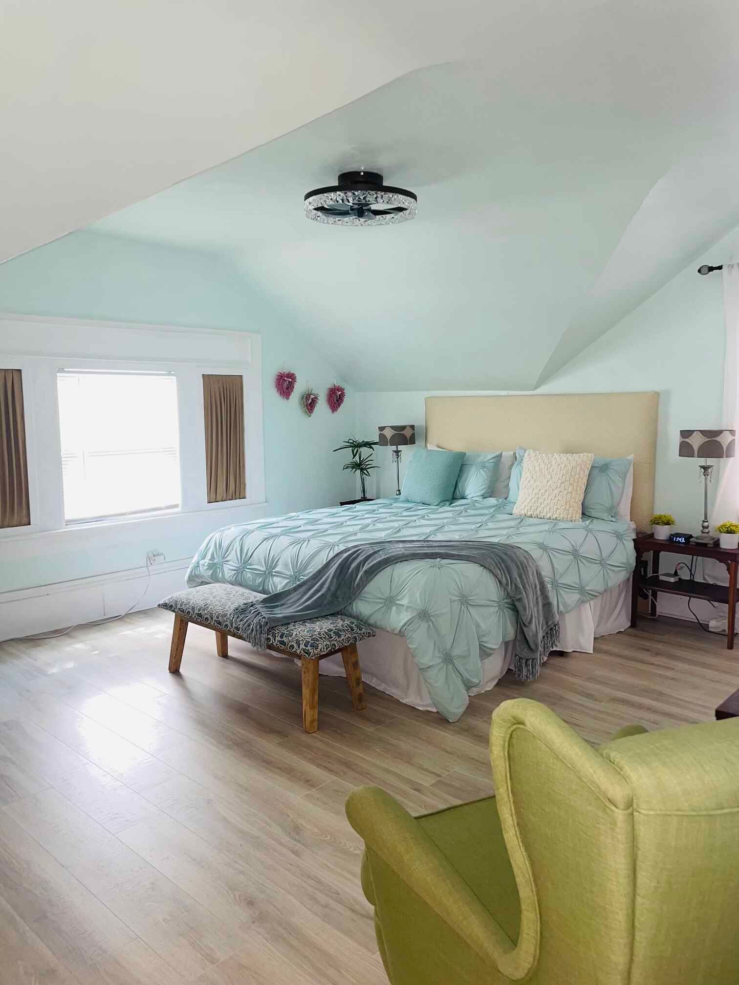 A bedroom with a large bed and a green chair.