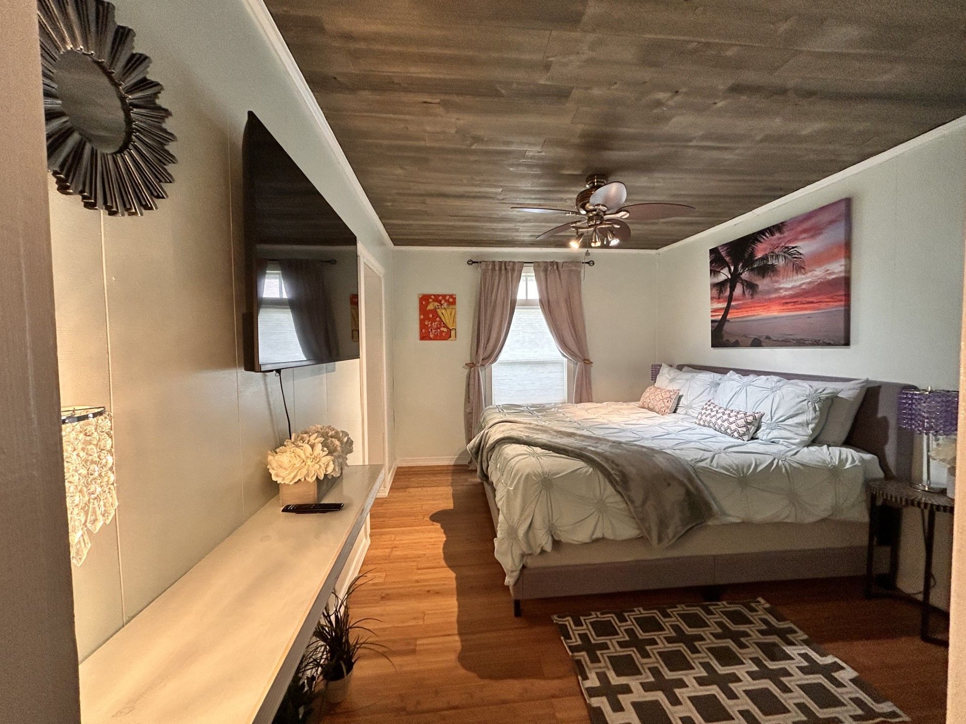A bedroom with a large bed and a flat screen tv on the wall.