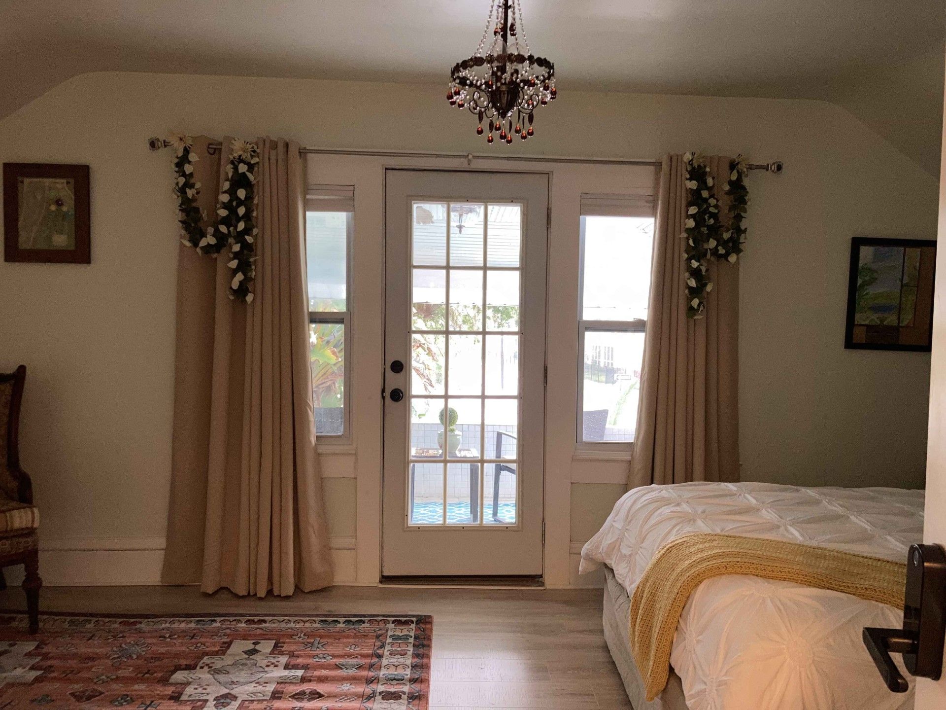 A bedroom with a bed , chair , rug and a chandelier.