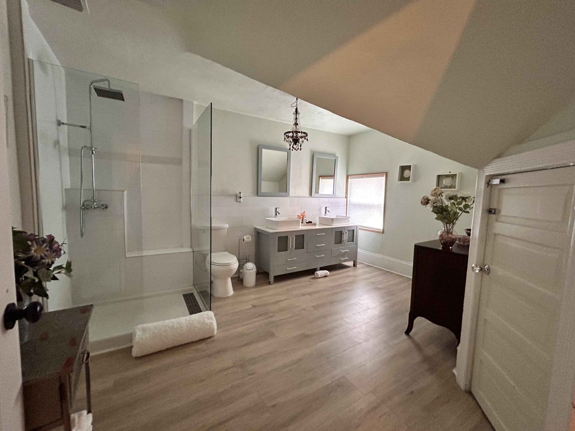 A bathroom with two sinks , a toilet , and a walk in shower.