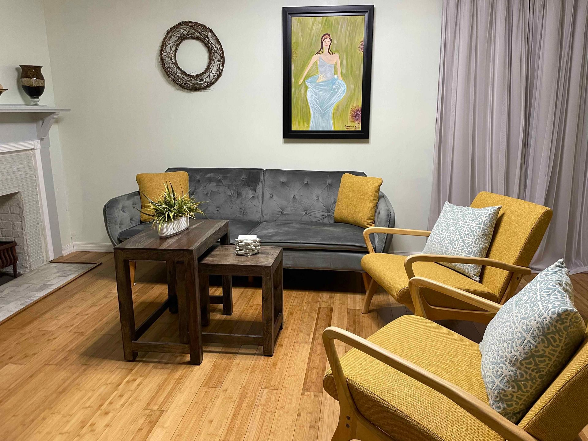 A living room with a couch , chairs , table and fireplace.